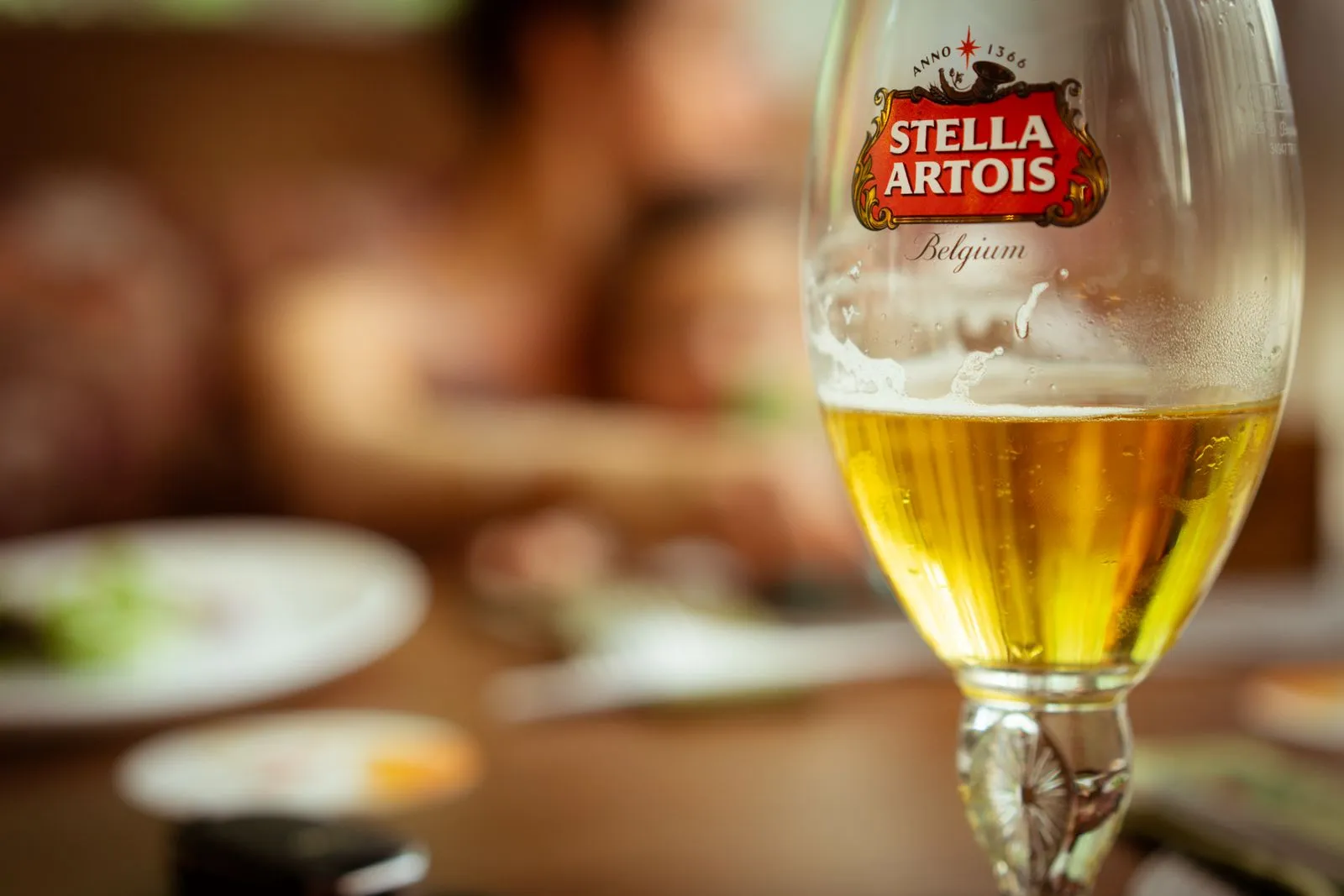 A chilled Stella Artois beer glass in a cozy pub with a blurred background, capturing the essence of relaxation.